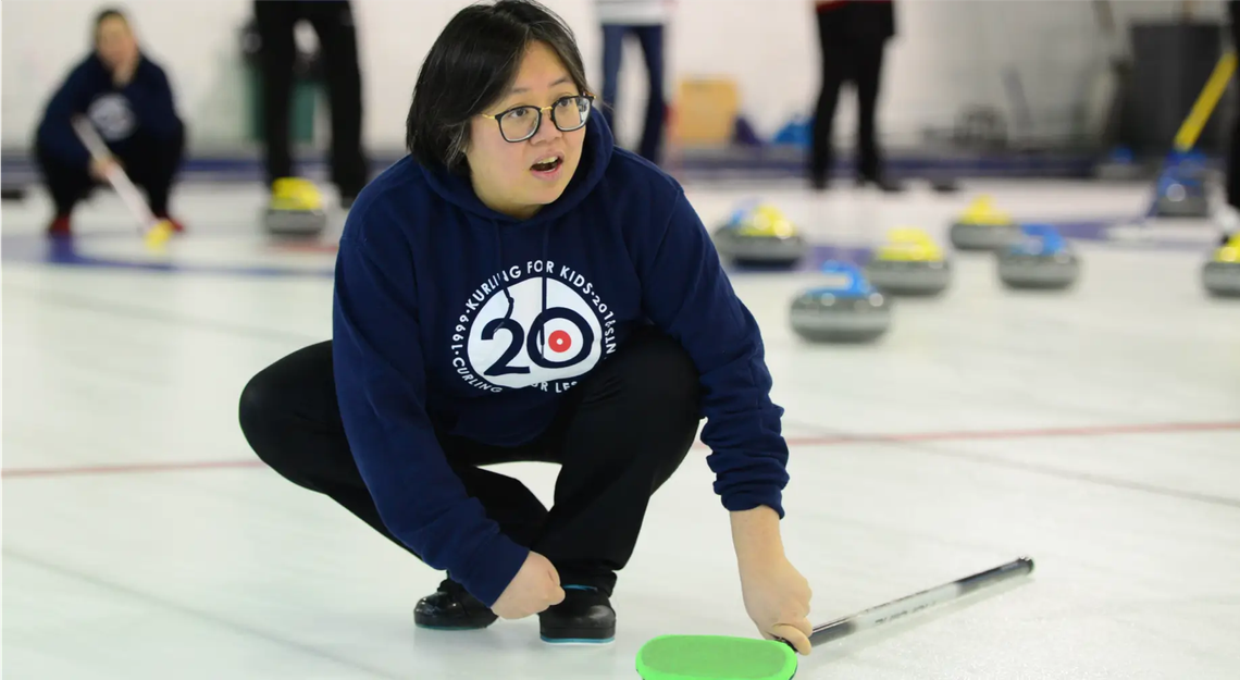 A curler crouched down on the ice
